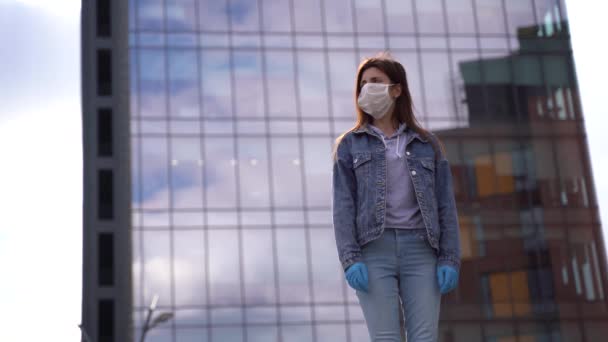 Concept - młoda kobieta w ochronnej masce medycznej na ulicy miejskiej, — Wideo stockowe