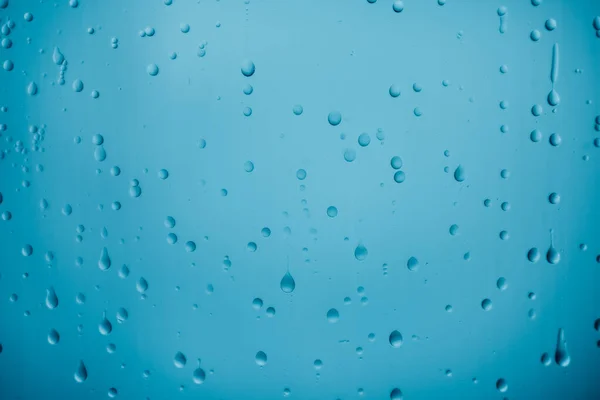 Капли воды на гладком синем стекле — стоковое фото
