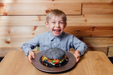 Büyük hamburgerli keyifli çocuk