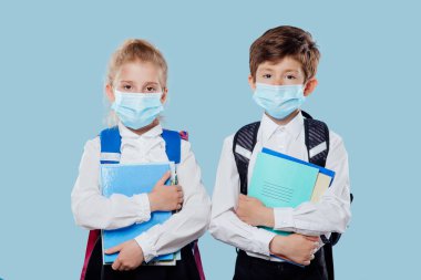 okul çocuğu ve okul kızı tıbbi maskeli ve sırt çantalı.