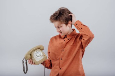 Kafası karışmış, telefonu eski, beyaz tenli bir çocuk.