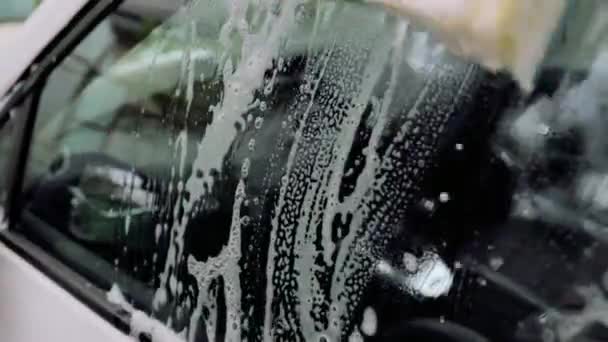 Yaklaş, süngerli adam eli araba camını yıkar. Otomobil servisi kavramı, — Stok video