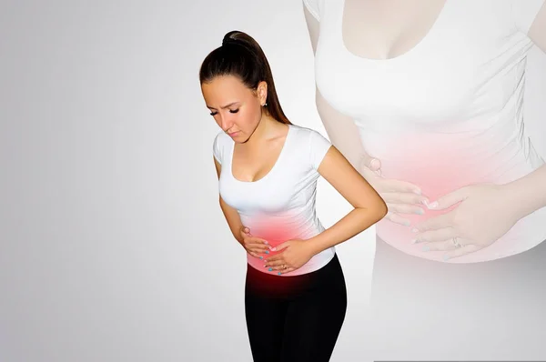 Abdominal pain. A young woman suffers from pain in the abdomen. The problem with digestion. The problem of women's health, the concept of menstruation. A place of pain marked with a red spot. Concept — Stock Photo, Image