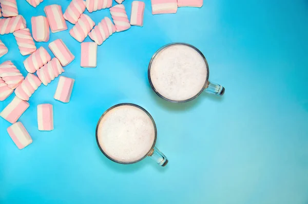 Heißgetränk Kakao oder Schokolade mit Milchcreme und Marshmallows in einer kleinen durchsichtigen Tasse auf blauem Hintergrund. Winter. Neujahr. flache Lageoberseite — Stockfoto