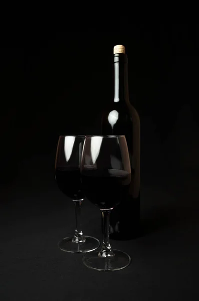 Красное вино. Бутылка и два бокала красного вина на черном фоне — стоковое фото