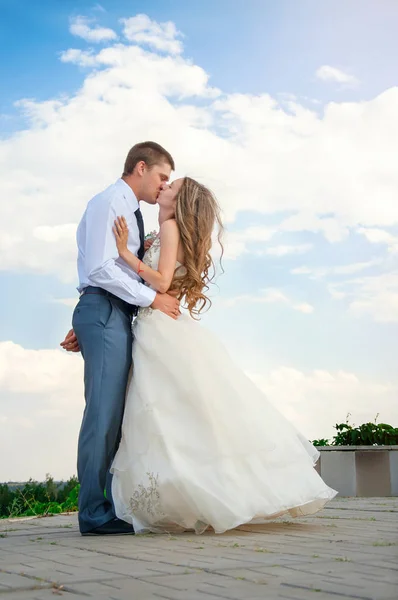 Düğün günü. Güzel gelin damat gökyüzü arka plan üzerinde kollarında — Stok fotoğraf