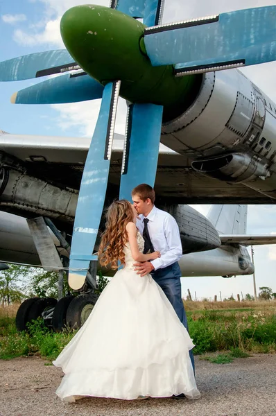 Την ημέρα του γάμου. Ευτυχισμένο ζευγάρι φιλιέται στο φόντο του αεροπλάνου — Φωτογραφία Αρχείου