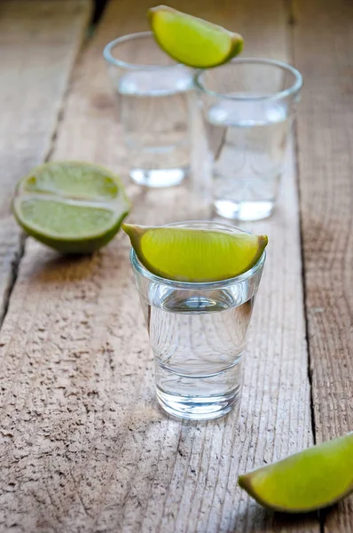 Alcohol Shot Drink. Silver Tequila with Lime on the Wooden Table