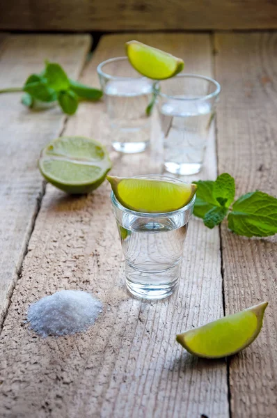 Alcohol Shot Drink. Silver Tequila with Lime, Salt and Green on the Wooden Table