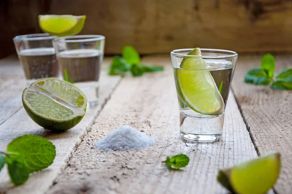 Alcohol Shot Drink. Silver Tequila with Lime, Salt and Green on the Wooden Table
