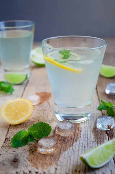 Cocktails d'été rafraîchissants avec glace aux agrumes et menthe sur table en bois — Photo