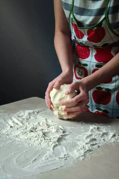 Frauenhände kneten den Teig mit Weißmehl. Strahllicht fällt im Dunkeln auf den Tisch — Stockfoto