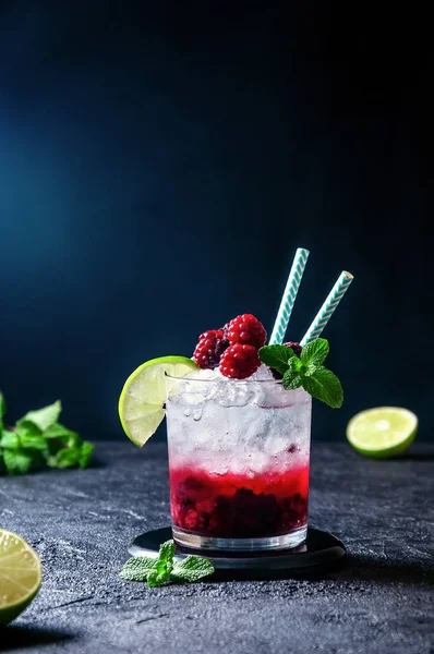 Cocktail au rhum ou vodka, soda, purée de framboises et mûres, chaux et menthe dans le verre sur fond gris foncé — Photo