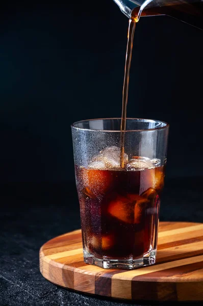 Iced Cola of Cold Coffee gieten in Tall Glass op donkere achtergrond. Concept Verfrissend zomerdrankje — Stockfoto