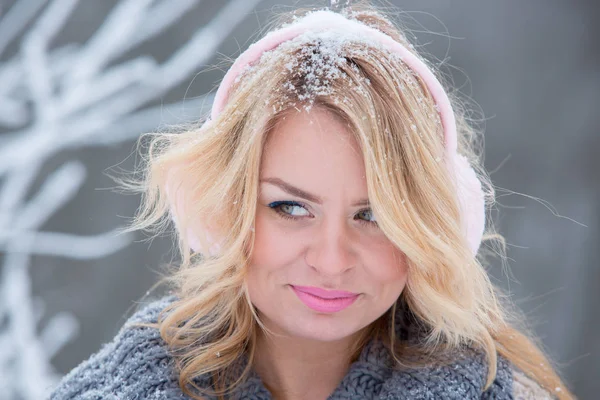 Mooi meisje in roze koptelefoon op de sjaal met sneeuw — Stockfoto