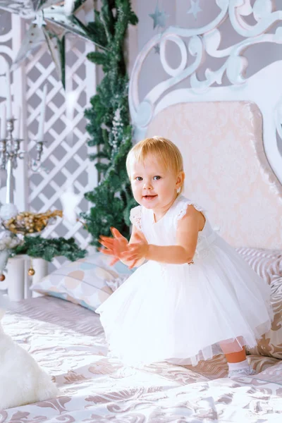 Niña feliz en vestido blanco de pie en la habitación decorada de Navidad — Foto de Stock