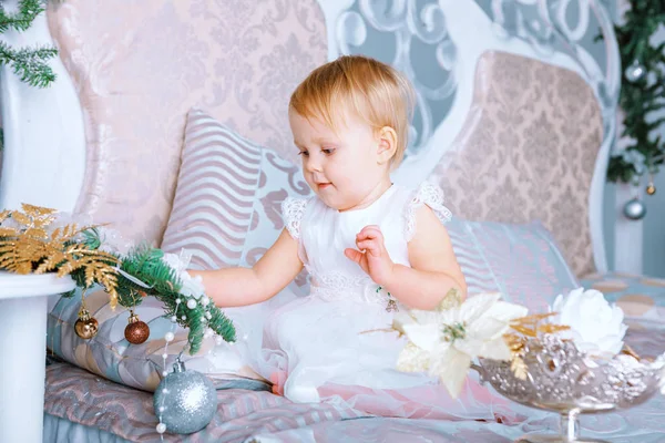 Niña feliz en vestido blanco decora el árbol en la habitación decorada de Navidad — Foto de Stock