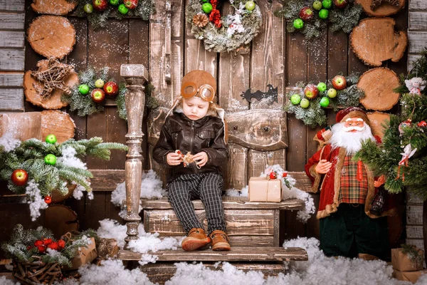 Braun deri ceket, pantolon ve bot üzerinde Noel süslemeleri poz pilot şapkası ile küçük iki yaşında bir çocuk giymiş