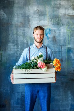 Ahşap kutu mavi zemin üzerine çiçekli tutan erkek çiçekçi