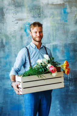 Ahşap kutu mavi zemin üzerine çiçekli tutan erkek çiçekçi