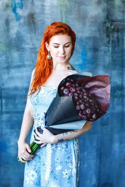 Karaktervolle romantische vrouwelijke vrouw houdt zwarte boeket van Calendula, aster donker paarse kleur op blauwe achtergrond — Stockfoto