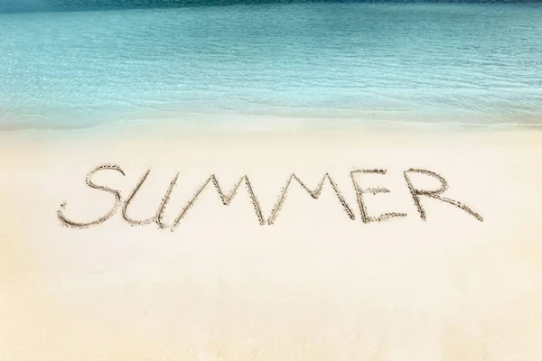 Het woord van de zomer op het strand zand geschreven. — Stockfoto