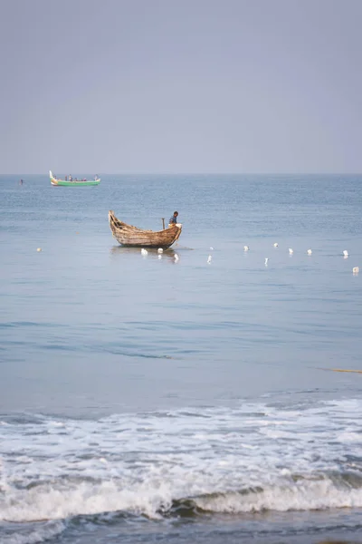 Fischer, der in einem traditionellen hölzernen Kanuboot auf dem blauen Indischen Ozean steht und Fische sichtet — Stockfoto