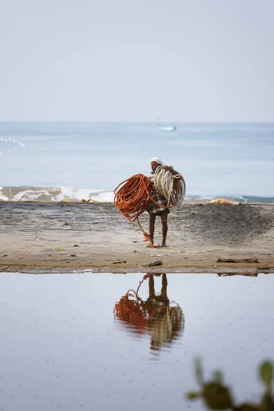 Індійська рибалки, несучи чистий мотузки, ходьба по піску, відбиття в заводах — стокове фото