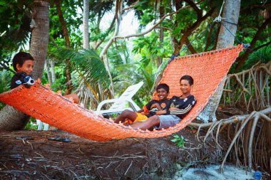 Children are resting in hammovk in the beach of island small village clipart