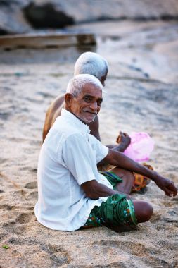 Mutlu Hint balıkçı portresi balık ağlarına ve mücadele bir tekne içinde Kerala Hindistan balıkçılık Körfez otururken unravels. Odayam beach, Varkala, Hindistan