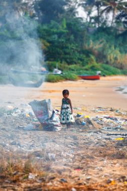 Kız çocuk çöp yığınları içinde şilep ile adaya annesi beach, Kollam üzerinde Kerala yanıyor