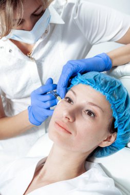 Doktor kozmetik uzmanı güzellik salonundaki kadın cildine Biyolojik Evrimi Yenileme yüz enjeksiyonu prosedürü uyguluyor.