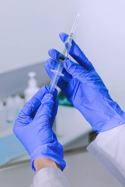 Sterile medicine equipment. Doctor wearing sterile blue gloves opening sterile medical needle syringe. Hands close-up