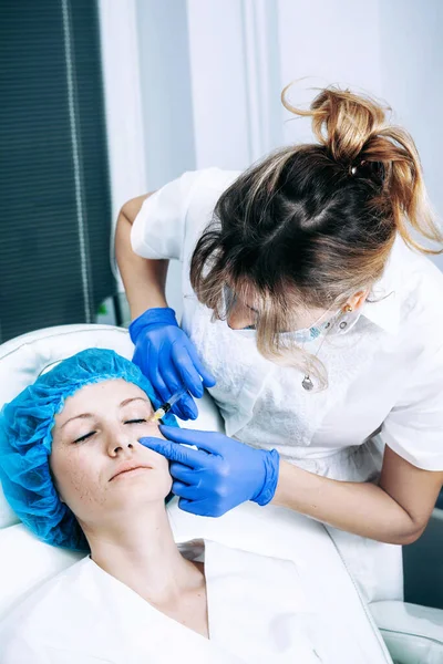 Косметолог делает омолаживающую процедуру биоревитализации кожи лица на женской коже в салоне красоты — стоковое фото