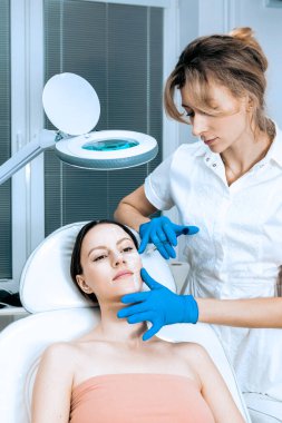 Doktor kozmetik uzmanı güzellik salonundaki kadın cildine Biyolojik Evrimi Yenileme yüz enjeksiyonu prosedürü uyguluyor.