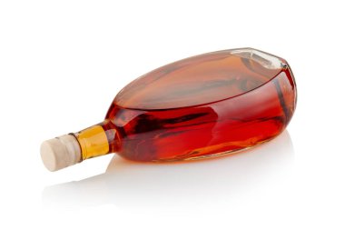 Beyaz yansıtıcı yüzeyde yatay duran bir şişe alkollü içecek.