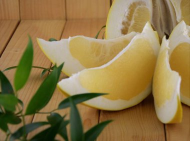 Bir buçuk pomelo ve onun kesme adet yeşil ahşap zemin üzerine yapraklar, pomelo kesmek kadar yakın