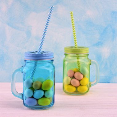 Renkli Paskalya yumurtaları ile gök mavi ve yeşil şeffaf cam kavanoz