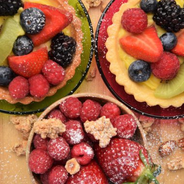 İki kek sepetleri krem ve taze çilek ile. Çilek, ahududu, yaban mersini, böğürtlen ve bazı müsli küçük tabak