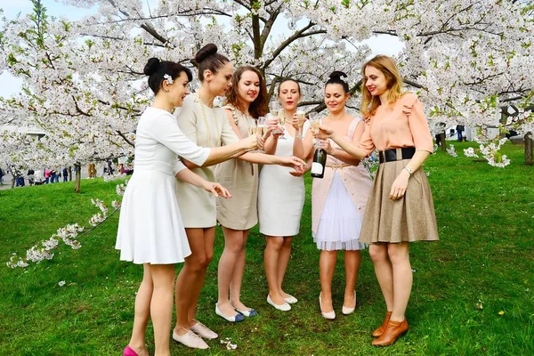 Girls with champagne celebrating in sakura's garden. — Stock Photo, Image