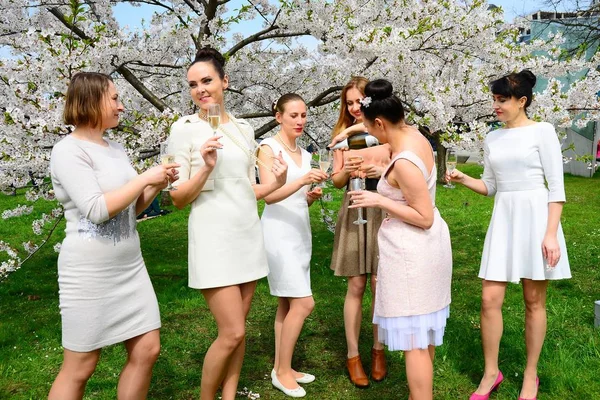Girls with champagne celebrating in sakura's garden. — Stock Photo, Image
