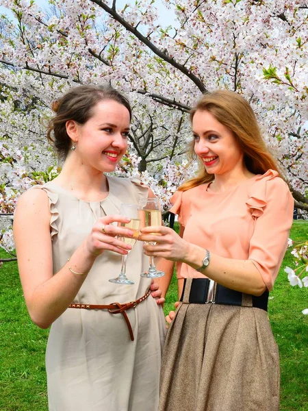 Girls with champagne celebrating in sakura's garden. — Stock Photo, Image