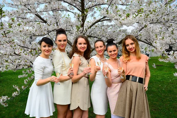 Girls with champagne celebrating in sakura's garden. — Stock Photo, Image