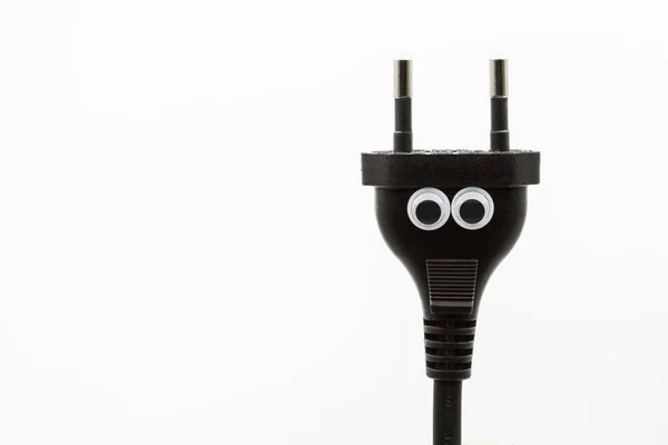 Black electric plug with googly eyes on white background - close up — Stock Photo, Image