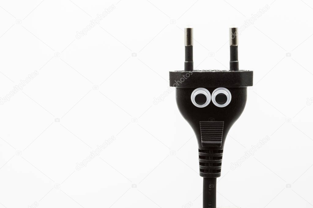 black electric plug with googly eyes on white background - close up