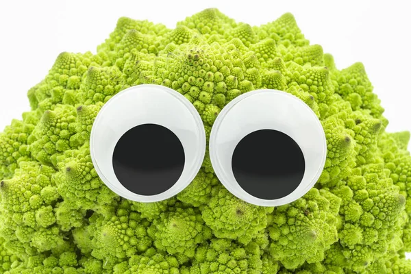 Grüner Blumenkohl mit googly Augen auf weißem Hintergrund lizenzfreie Stockfotos