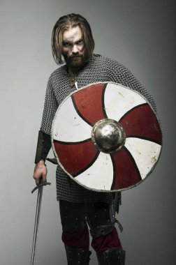 Kılıç ve kalkan gri arka plan üzerinde tutarak Viking