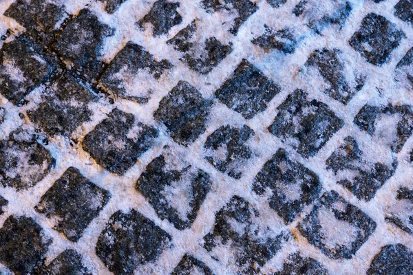 The texture of paving stone masonry sprinkled with snow, close up. — Stock Photo, Image