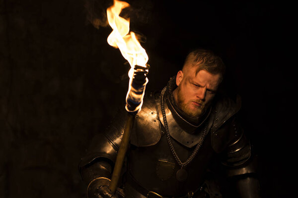Knight with a torch at night on a wall background Stock Image