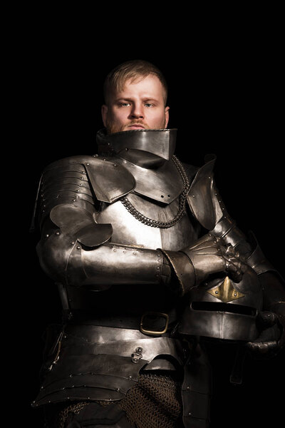 Knight in armour after battle on the black background